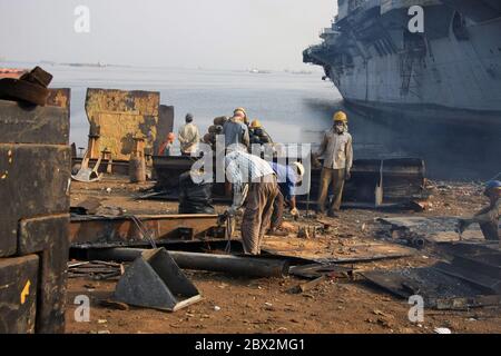 Chantier naval de Darukhana, Mumbai, Inde – INS Vikrant démantèlement avec ferraille et ouvriers en arrière-plan Banque D'Images