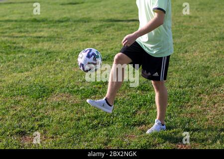 Un jeune garçon tenant une balle de football sur un terrain Banque D'Images