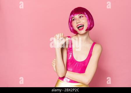 Image de la joyeuse partie fille portant perruque rire et pointant le pouce sur elle-même isolée sur fond rose Banque D'Images