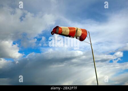 Sac à vent pour la navigation maritime. La chaussette rouge et blanche souffle sur un ciel bleu Banque D'Images