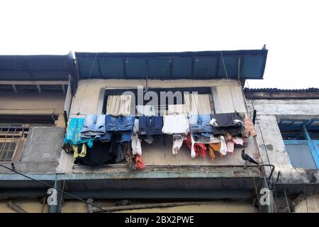 Ligne de lavage pleine de vêtements suspendus à l'extérieur d'une fenêtre de taudis à Mumbai, Inde Banque D'Images