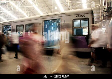 Flou de mouvement des personnes se déplaçant sur un trajet quotidien en Inde, avec un train en arrière-plan Banque D'Images