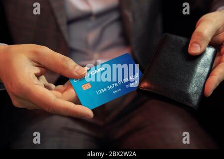 Main met la carte de crédit dans le portefeuille. La main d'homme d'affaires met hors carte de crédit créé dans le programme graphique de portefeuille en cuir. Banque D'Images