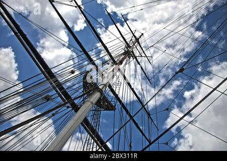 Mât de voile en bois avec gréement et étincelles mais avec des voiles en bas et ciel bleu nuageux - vue de la plate-forme vers le haut Banque D'Images