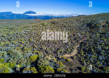 France, Ile de la Réunion (département français d'outre-mer), Parc national de la Réunion classé au patrimoine mondial par l'UNESCO, sur les pentes du volcan Piton de la Fournaise, randonneur sur le sentier thératoire Ste-Thérèse au-dessus de la Plaine des Sables, le Piton des Neiges au nord (vue aérienne) Banque D'Images