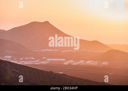 Espagne, îles Canaries, île Lanzarote, coucher de soleil sur la vallée viticole de la Geria, villages d'Uga et Yaiza et Montana de la Cinta en arrière-plan Banque D'Images