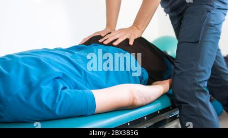 Physiothérapeute s'exerçant avec une personne handicapée sur une table de thérapie. Banque D'Images