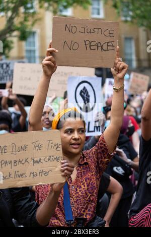 Une femme qui prend le genou et tient un panneau pendant la Black Lives Matters proteste devant 10 Downing Street, Londres, 3 juin 2020 Banque D'Images