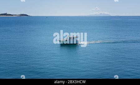 Un bateau de pêche qui retourne à la marina après une journée sur l'eau d'une mer étincelant Banque D'Images