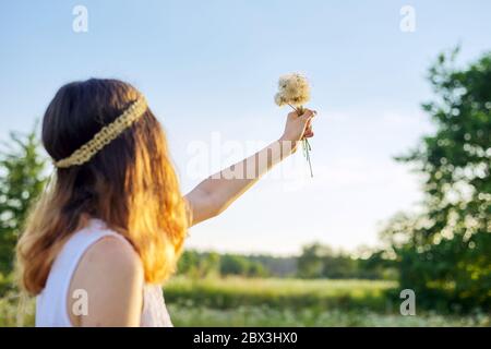 Adolescente avec la coiffure hippie tenant des pissenlits secs dans sa main Banque D'Images