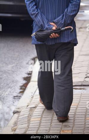 Vue arrière de l'homme marchant dans la rue avec parasol, foyer sélectif Banque D'Images