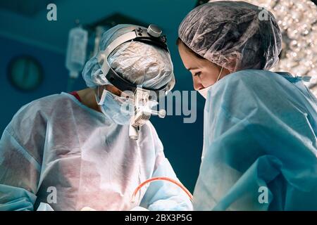 Gros plan dans la salle d'opération, l'assistant remet les instruments aux chirurgiens pendant le fonctionnement. Chirurgie en cours. Médecins professionnels Banque D'Images