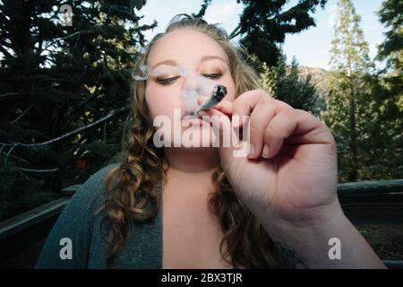 Une jeune femme fume une cigarette de cannabis Banque D'Images