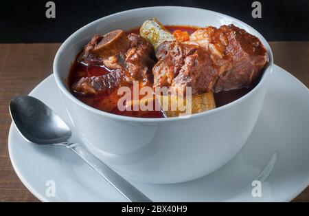 Cuisine mexicaine concept, soupe de côtes de bœuf dans un bol blanc, avec une salsa épicée à base de guajillo du chili et d'autres piments chauds et tomates avec des légumes. Banque D'Images