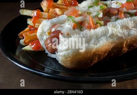 Gros plan ou macro-photographie de Hot Dog avec légumes sur le dessus et frites avec ketchup sur le côté Banque D'Images