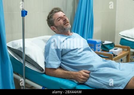 homme peur et inquiet dans la douleur à la chambre d'hôpital - attrayant blessé homme allongé sur le lit souffrant de problèmes douloureux se sentant malade et stressé après avoir souffert Banque D'Images