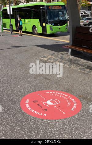 Des panneaux ronds sur le trottoir conseillant de maintenir la distance et de porter des masques sur les transports publics à la gare routière de Los Cristianos pendant la phase deux de-escala Banque D'Images