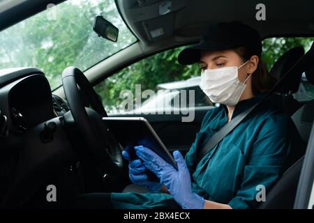 Femme courier assise dans une voiture et regardant une tablette numérique Banque D'Images