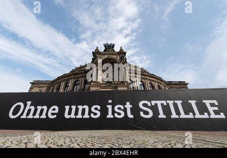 Dresde, Allemagne. 05e juin 2020. Une bannière avec l'inscription 'Ohne uns ist Stille' ('sans nous il y a le silence') a été accrochée sur une clôture de construction en face du Semperoper sur Theaterplatz avant le début d'une manifestation conjointe par des artistes, des organisateurs d'événements et des entreprises dans l'industrie de l'événement. Avec un défilé de camions de 30 véhicules et une action avec 1000 chaises vides et 1000 personnes, l'objectif est d'attirer l'attention sur les problèmes et l'importance de l'industrie de l'événement. Crédit : Robert Michael/dpa-Zentralbild/dpa/Alay Live News Banque D'Images