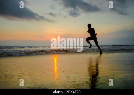 Silhouette de jeune coupe attrayante athlétique et noir fort afro américain courir au coucher du soleil plage entraînement dur et sprinting sur l'eau de mer en pro Banque D'Images