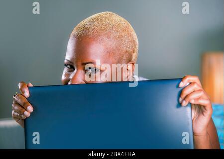 gros plan portrait de style de vie de jeune femme afro-américaine élégante et heureuse noire posant amusant se cacher derrière l'écran d'ordinateur portable smil Banque D'Images