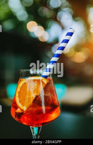 Verre d'Aperol Spritz et paille bleue, cocktail italien. Texture fine du grain du film. Banque D'Images