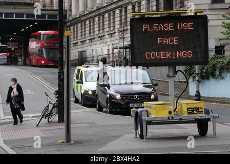 Une affiche demandant aux gens d'utiliser des revêtements de visage à l'extérieur de la gare de Waterloo à Londres, suite à l'annonce que le port d'un revêtement de visage sera obligatoire pour les passagers des transports en commun en Angleterre à partir de juin 15. Banque D'Images