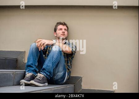 jeune homme triste et désespéré assis à l'extérieur dans les escaliers de rue souffrant d'anxiété et de dépression se sentant misérable pleurer abandonné dans le chômage et Banque D'Images