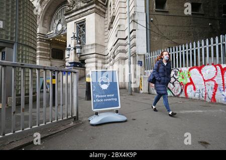 Une affiche demandant aux gens d'utiliser des revêtements de visage à l'extérieur de la gare de Waterloo à Londres, suite à l'annonce que le port d'un revêtement de visage sera obligatoire pour les passagers des transports en commun en Angleterre à partir de juin 15. Banque D'Images