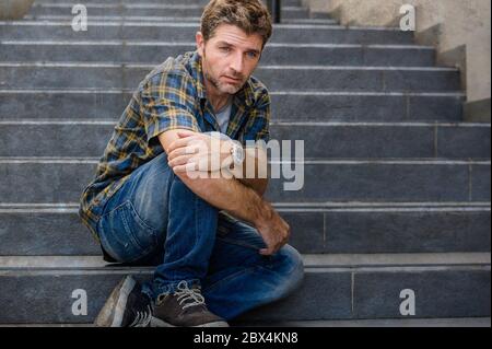 jeune homme triste et désespéré assis à l'extérieur dans les escaliers de rue souffrant d'anxiété et de dépression se sentant misérable pleurer abandonné dans le chômage et Banque D'Images