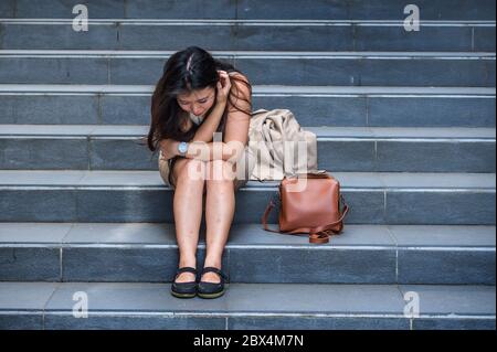 Jeune femme d'affaires japonaise asiatique désespéré et déprimée pleure seule assise dans un escalier de rue souffrant de stress et de dépression crise étant victi Banque D'Images