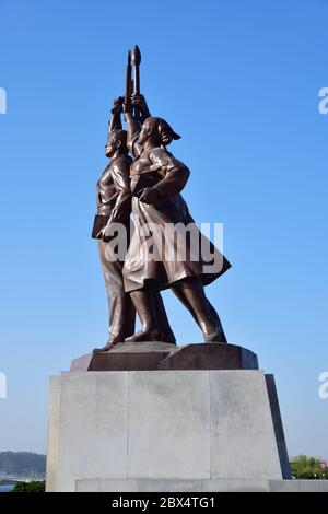 Pyongyang, Corée du Nord - 1er mai 2019 : statue de Juche composée de trois figures idéalisées, chacune tenant un outil - un marteau (ouvrier), une faucille (paysan), Banque D'Images