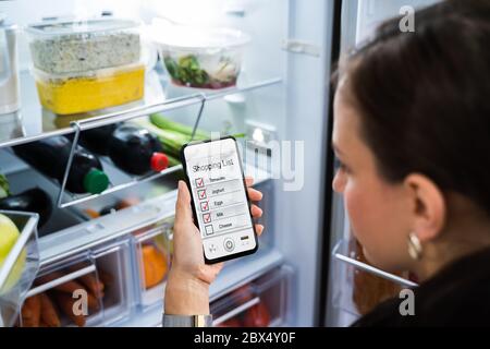 Application pratique pour le téléphone de la liste de courses d'épicerie près du réfrigérateur Banque D'Images