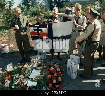 Berlin-Spandau / Nazis / groupes de droite 20.8.1987 devant la prison des criminels de guerre de Spandau, Rudolf Hess vient de mourir. Les groupes de droite se rassemblent en deuil. Le jeune radical de droite Michael Wendt (à droite) avec le drapeau de guerre de Reich et le salut de Kuehnen, une variante du salut d'Hitler, qui a été interdit. Un policier demande ce que c'est. Fleurs devant pour Hess. // nazi / fascisme / *** Légende locale *** la prison pour les criminels de guerre à Berlin-Spandau. Le dernier prisonnier, Rudolf Hess, est mort juste après 46 ans dans la prison montrée en arrière-plan. Aile droite Banque D'Images