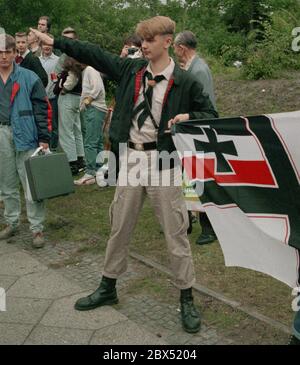 Berlin-Spandau / Nazis / groupes de droite 20.8.1987 devant la prison des criminels de guerre de Spandau, Rudolf Hess vient de mourir. Les groupes de droite se rassemblent en deuil. Le jeune radical de droite Michael Wendt (à droite) avec le drapeau de guerre de Reich et le salut de Kuehnen, une variante du salut d'Hitler, qui a été interdit. Un policier demande ce que c'est. Fleurs devant pour Hess. // nazi / fascisme / *** Légende locale *** la prison pour les criminels de guerre à Berlin-Spandau. Le dernier prisonnier, Rudolf Hess, est mort juste après 46 ans dans la prison montrée en arrière-plan. Aile droite Banque D'Images