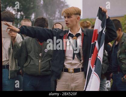 Berlin-Spandau / Nazis / groupes de droite 20.8.1987 devant la prison des criminels de guerre de Spandau, Rudolf Hess vient de mourir. Les groupes de droite se rassemblent en deuil. Le jeune radical de droite Michael Wendt (à droite) avec le drapeau de guerre de Reich et le salut de Kuehnen, une variante du salut d'Hitler, qui a été interdit. Un policier demande ce que c'est. Fleurs devant pour Hess. // nazi / fascisme / *** Légende locale *** la prison pour les criminels de guerre à Berlin-Spandau. Le dernier prisonnier, Rudolf Hess, est mort juste après 46 ans dans la prison montrée en arrière-plan. Aile droite Banque D'Images