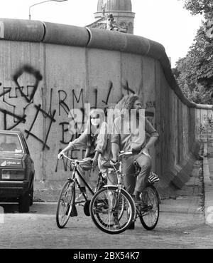 Quartiers de Berlin / Wall / Kreuzberg / Mitte/ 1983 Legiendamm, devant deux habitants typiques du quartier alternatif, au-dessus d'un garde-frontière de la RDA surplombe le mur // RDA / Border / [traduction automatique] Banque D'Images