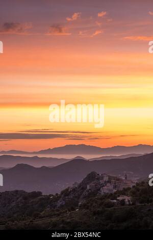 Aube se brisant sur la côte silhouetée du Cap Corse et l'ancien village de montagne de Speloncato en Corse Banque D'Images