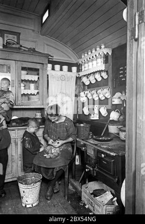 Une mère et ses deux enfants épluchent les pommes de terre. Ils vivent dans une voiture express à Wittenberg, qui est utilisée comme hébergement d'urgence. Dans la voiture il ya une cuisine complète avec cuisinière, placard, un pack de détergent Persil pour stocker les charbons etc Banque D'Images