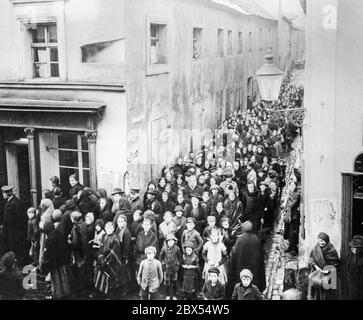 Une longue file d'attente s'est formée devant une boulangerie dans une allée. Les gens attendent pour acheter de la farine. En raison de la longue guerre, pour laquelle les dirigeants politiques et militaires en Allemagne ne prennent pas de précautions, il y a eu des problèmes d'approvisionnement. Ces derniers ont culminé dans le 'Kohlruebenwinter' ('Turnip Winter') du 1917/1918, au cours duquel de nombreuses personnes âgées, malades et enfants sont morts d'épuisement et de malnutrition. Banque D'Images