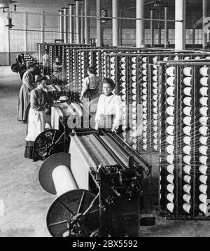 Dans une filature de coton, les travailleuses utilisent les machines de filature qui serpentent le fil dans le tissu. La photo a été prise en 1905. Banque D'Images