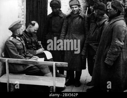 Deux officiers allemands interrogent cinq prisonniers soviétiques à Cholm. Pendant la bataille d'encerclement de Kholm, le 'Kampfgruppe Scherer' a défendu avec succès la ville pendant 105 jours. (Photo de la compagnie de propagande (PK) par le correspondant de guerre Richard Muck, qui a pris l'avion dans la poche au début du mois de mars). Banque D'Images