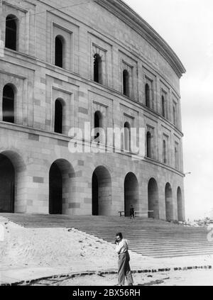 Vue sur la façade du bâtiment modèle de 40 m de haut du Kongresshalle, conçu par les architectes Ludwig Ruff et Franz Ruff, avant le Congrès du Parti Reich. Au premier plan est un photographe, au fond un garde de la SS. Banque D'Images