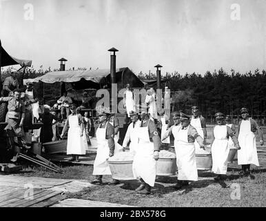 Dans le camp Harnischschlag du NSDAP de Berlin, la cuisine de 10000 hommes est faite dans des tentes de cuisine. Les aides de cuisine portent la choucroute dans de grands bols au centième poids. Banque D'Images