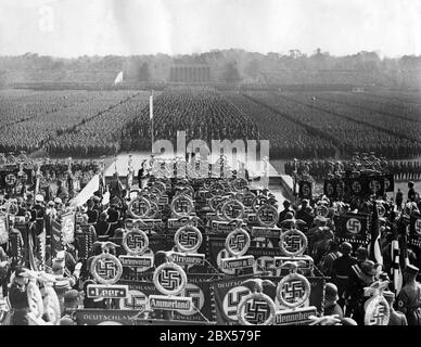 Aperçu de l'appel général de SS, sa, NSKK et NSFK dans le Luitpold Arena sur le terrain du rassemblement du Parti nazi de Nuremberg pendant la marche du drapeau. Adolf Hitler est debout sur la chaire. Au premier plan se trouvent les normes de la SS et de la sa (Leer, Ammerland, Henneberg, Krems, Marienwerder, Bremen, Wiener Neustadt, Kyffhaeuaser, Mittelweser), en arrière-plan, la Ehrenhalle (salle d'honneur). Banque D'Images