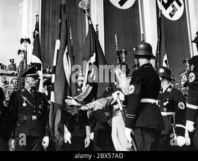 À la tribune de l'arène de Luitpold, Adolf Hitler consacre de nouveaux drapeaux de la SS avec l'aide du drapeau du sang. Banque D'Images