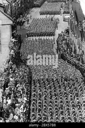 Vue sur la longue procession des troupes de sa, qui s'étend de la Fleischbruecke à la place du marché principal de Nuremberg à travers la foule. Adolf Hitler prend le salut debout dans une automobile sur ce qu'on appelle Adolf-Hitler-Platz. Un groupe de musique est en cours de lecture sur le côté gauche de la place. Banque D'Images