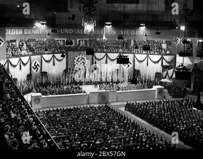 Le Front travailliste allemand a organisé un Gauappell le 22 octobre 1943 dans le Sportpalast de Berlin. Depuis que Goebbels avait déclaré la guerre totale au même endroit la même année, le ministre des armements Albert Speer avait essayé de regrouper toutes ses forces afin de pouvoir garantir des approvisionnements pour les troupes de combat. Le symbole de la croix centrale dans la roue dentée est le « drapeau d'usine » du DAF. Banque D'Images