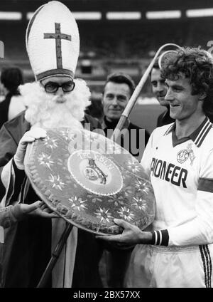 Le capitaine de l'équipe de Koeln, Reiner Bonhof, reçoit du pain d'épice géant de Saint Nicholas, Duesseldorf contre 1. FC Koeln, Bundesliga, saison 1980/1981, Fortuna Duesseldorf contre 1. FC Koeln 0: 0, Rheinstadion. Banque D'Images