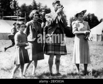 La princesse Margaret Rose, la princesse Elizabeth, le roi George VI dans un four balmoral féminin et la reine Elizabeth visitant le camp des garçons, qui a été initié par le roi, à Abergeldie. Le roi filme les jeunes garçons avec sa caméra lors d'une représentation de « sous l'arbre de Chestnut étalant ». Banque D'Images